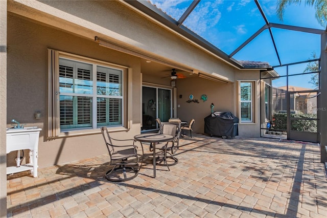 view of patio with glass enclosure, area for grilling, and ceiling fan