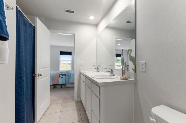 bathroom with toilet, vanity, and tile patterned floors