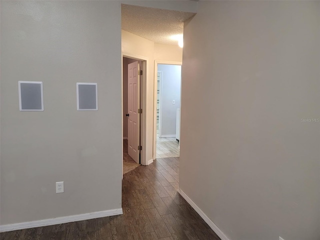 corridor with a textured ceiling and dark hardwood / wood-style floors