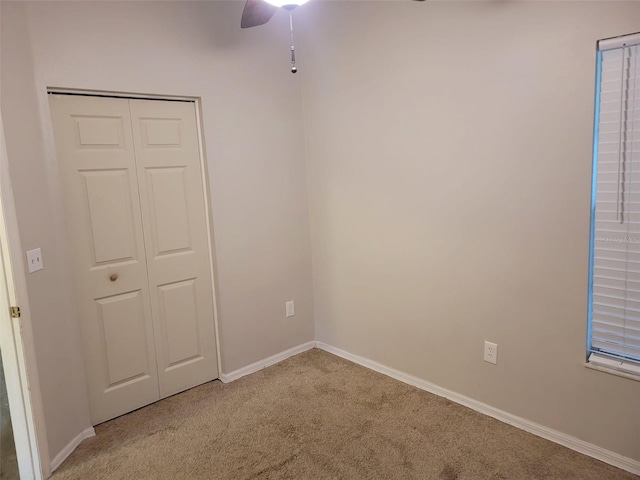 unfurnished bedroom with ceiling fan, light carpet, and a closet