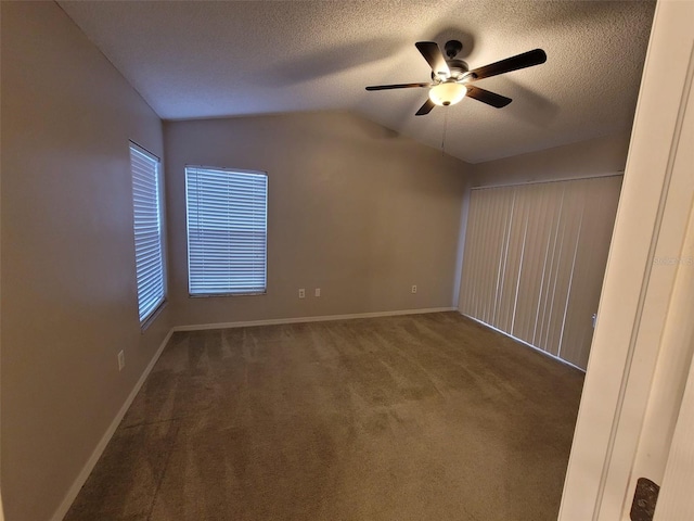 carpeted spare room featuring ceiling fan, vaulted ceiling, and a textured ceiling