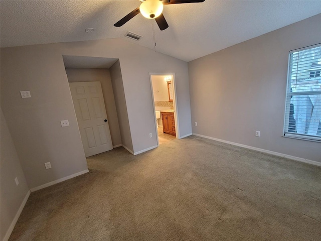 unfurnished bedroom with connected bathroom, vaulted ceiling, ceiling fan, a textured ceiling, and light carpet