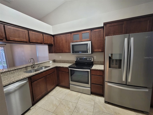 kitchen with appliances with stainless steel finishes, sink, vaulted ceiling, and light stone countertops