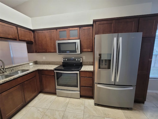 kitchen featuring sink, light stone countertops, and stainless steel appliances