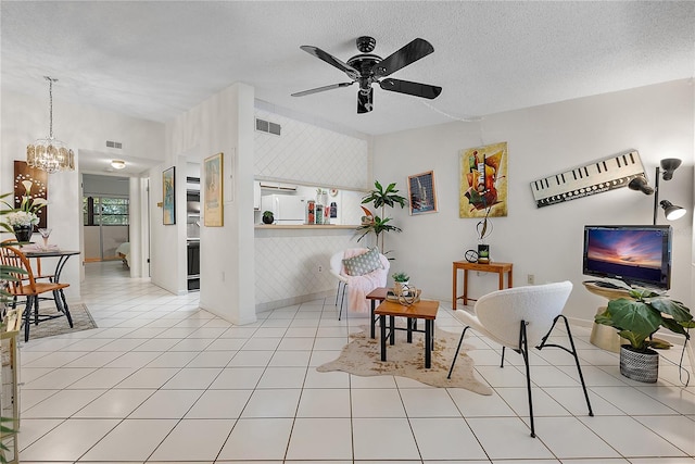 living area with light tile patterned flooring, ceiling fan with notable chandelier, and a textured ceiling