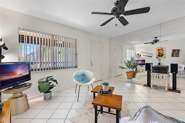 living room featuring ceiling fan, light tile patterned flooring, and a textured ceiling