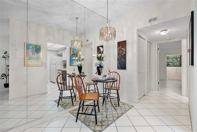 dining area with light tile patterned floors, a textured ceiling, and an inviting chandelier