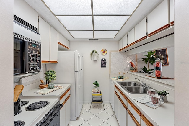 kitchen featuring white cabinets, sink, light tile patterned floors, tasteful backsplash, and range