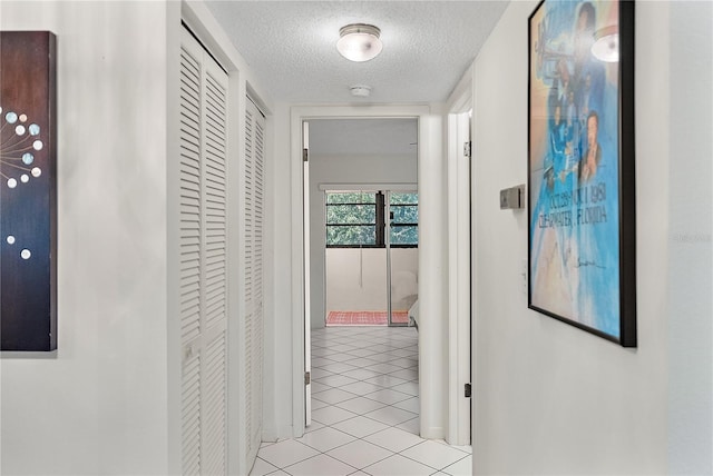 hall featuring light tile patterned floors and a textured ceiling