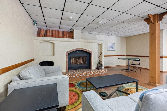 living room with a paneled ceiling and a fireplace