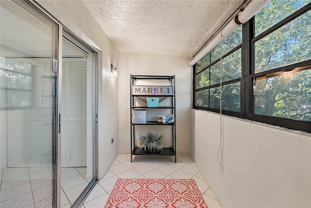 hall featuring a textured ceiling and light tile patterned flooring