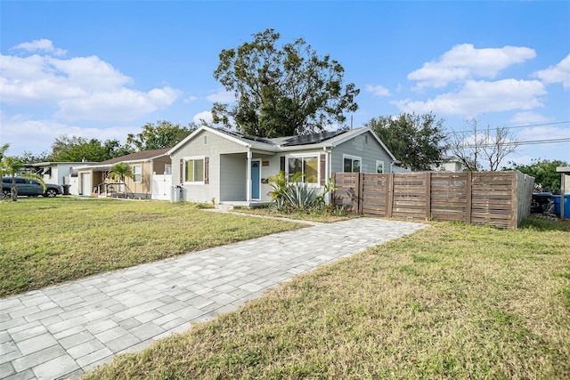 ranch-style home featuring solar panels and a front lawn