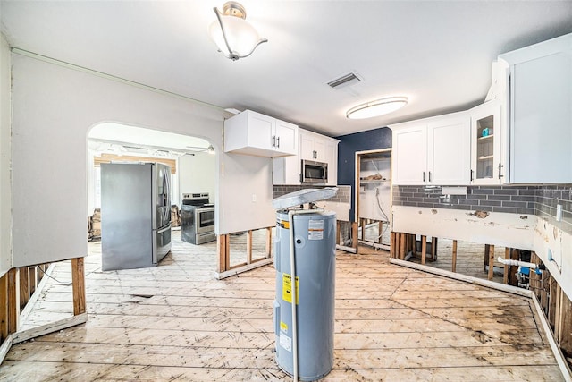 kitchen with white cabinets, electric water heater, appliances with stainless steel finishes, and tasteful backsplash