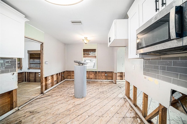 kitchen featuring white cabinets, light wood-type flooring, backsplash, and wooden walls