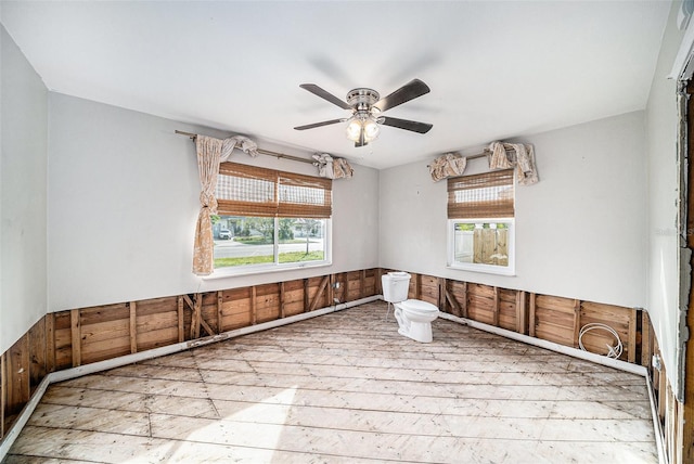 empty room featuring ceiling fan and wood walls