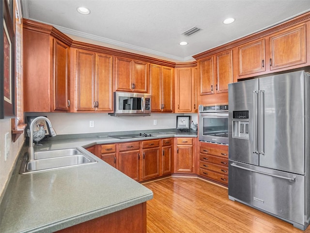 kitchen with sink, ornamental molding, stainless steel appliances, and light hardwood / wood-style flooring