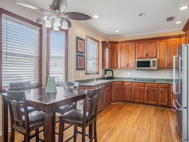 kitchen with sink, light hardwood / wood-style flooring, ceiling fan, ornamental molding, and appliances with stainless steel finishes