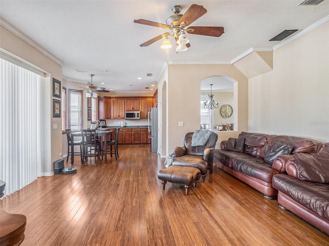 living room with hardwood / wood-style flooring, ceiling fan with notable chandelier, and crown molding