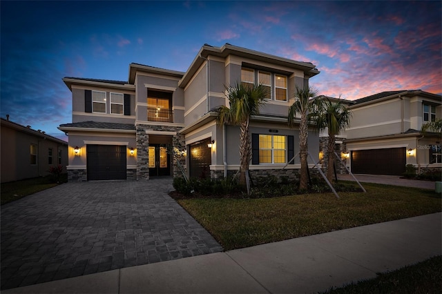 view of front of house featuring a balcony, a yard, and a garage