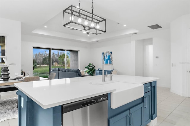 kitchen featuring stainless steel dishwasher, a center island with sink, a tray ceiling, and pendant lighting