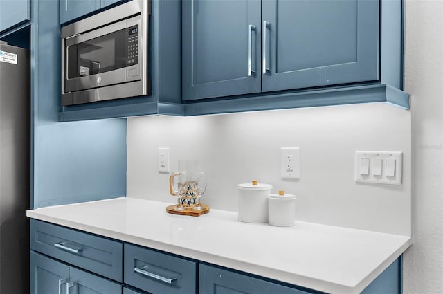 bar with stainless steel appliances and blue cabinetry