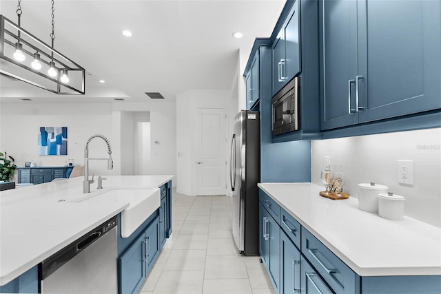 kitchen featuring appliances with stainless steel finishes, pendant lighting, blue cabinetry, and sink