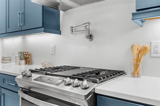 kitchen featuring stainless steel gas stove, blue cabinetry, and wall chimney exhaust hood