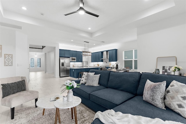 tiled living room featuring ceiling fan and a tray ceiling