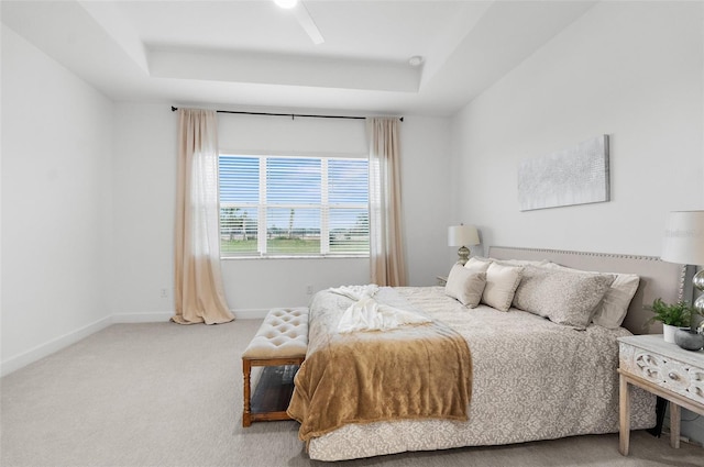 bedroom featuring ceiling fan, carpet flooring, and a tray ceiling