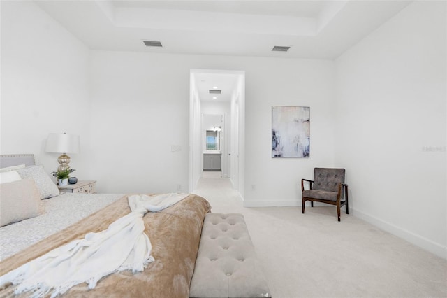 bedroom with light colored carpet and a tray ceiling