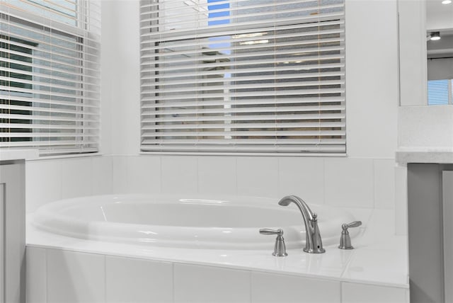 bathroom featuring tiled tub and vanity