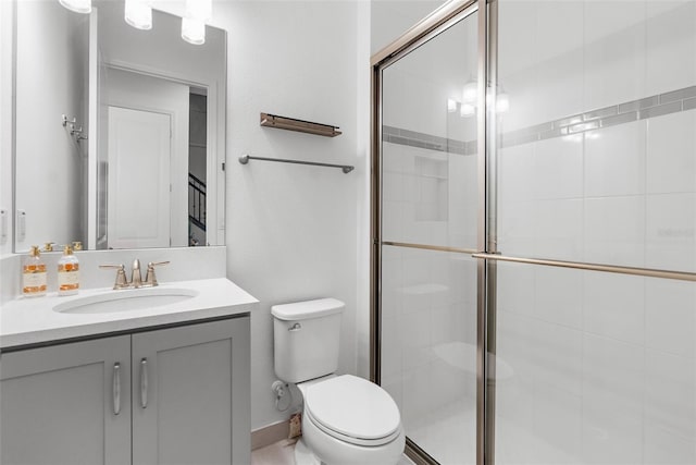 bathroom with toilet, a shower with shower door, and vanity