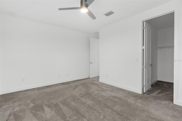 unfurnished bedroom with ceiling fan, a walk in closet, a closet, and carpet flooring