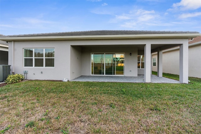 back of property with a lawn, central AC, and a patio