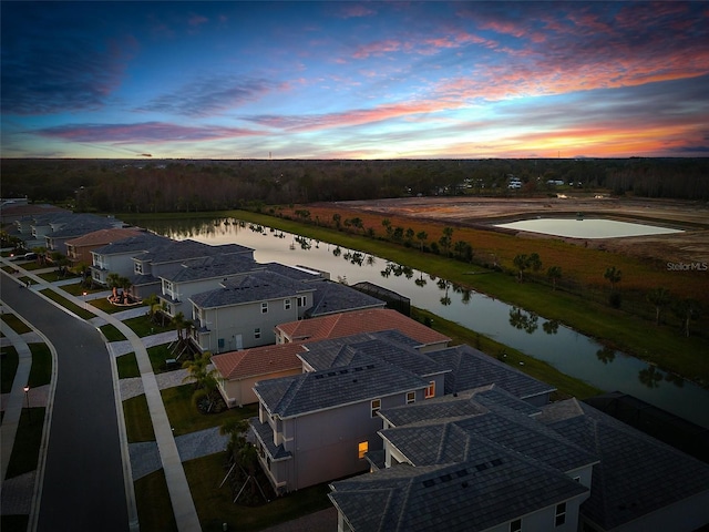 aerial view at dusk featuring a water view