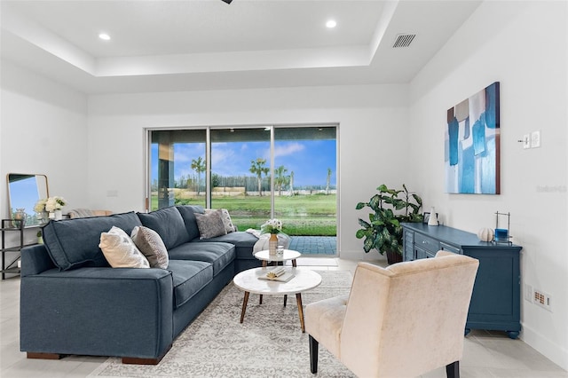 living room featuring a tray ceiling and light tile patterned floors