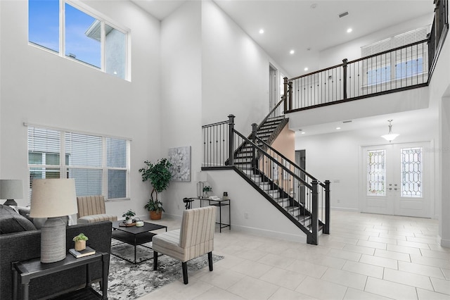 tiled living room with a towering ceiling and french doors