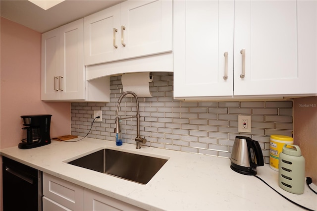 kitchen with sink, white cabinetry, tasteful backsplash, black dishwasher, and light stone countertops