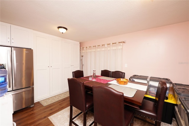 dining room featuring a textured ceiling and dark hardwood / wood-style flooring