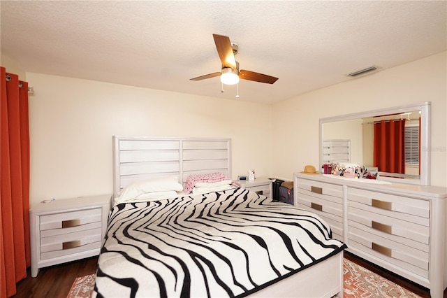 bedroom with ceiling fan, dark wood-type flooring, and a textured ceiling