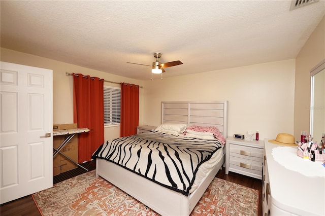 bedroom with ceiling fan, dark hardwood / wood-style floors, and a textured ceiling