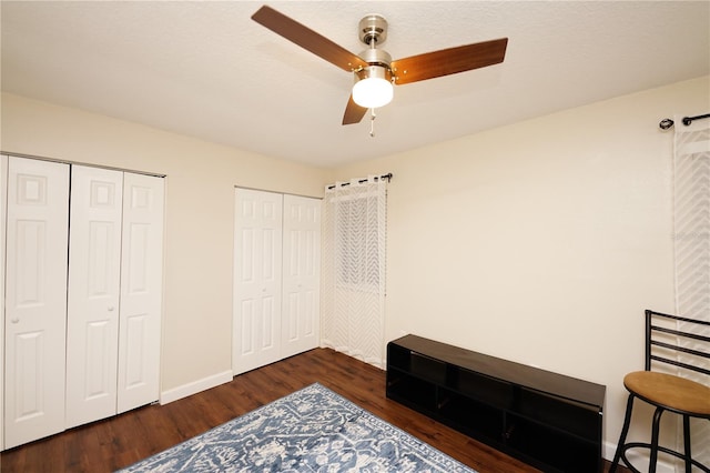 bedroom featuring multiple closets, ceiling fan, and dark wood-type flooring