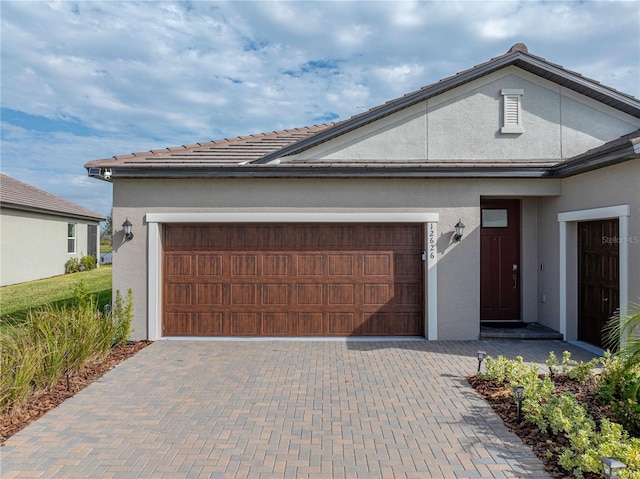 single story home with a garage, decorative driveway, and stucco siding