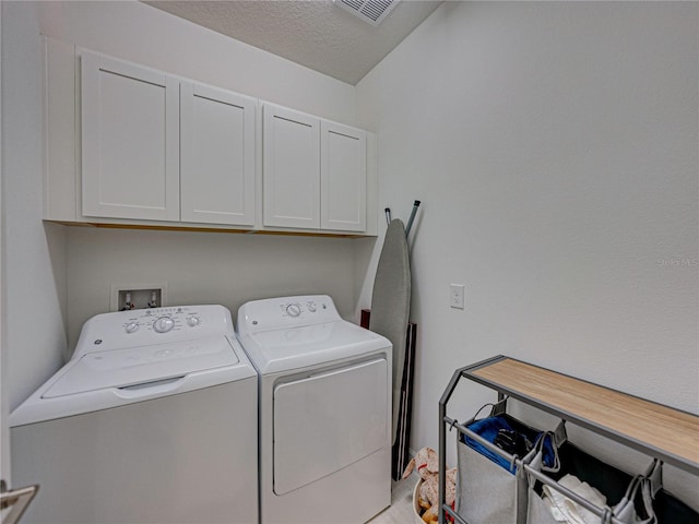 clothes washing area with separate washer and dryer, cabinets, and a textured ceiling