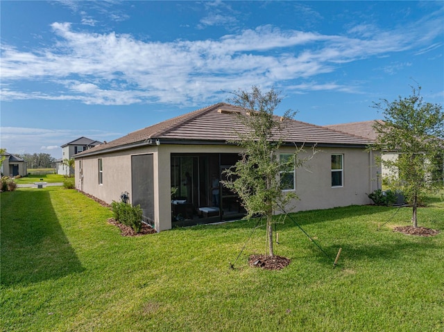 back of property featuring a sunroom and a lawn