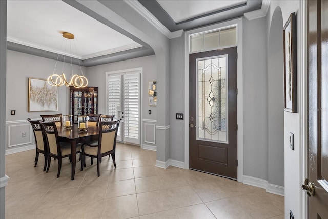 tiled foyer with an inviting chandelier, ornamental molding, and a tray ceiling