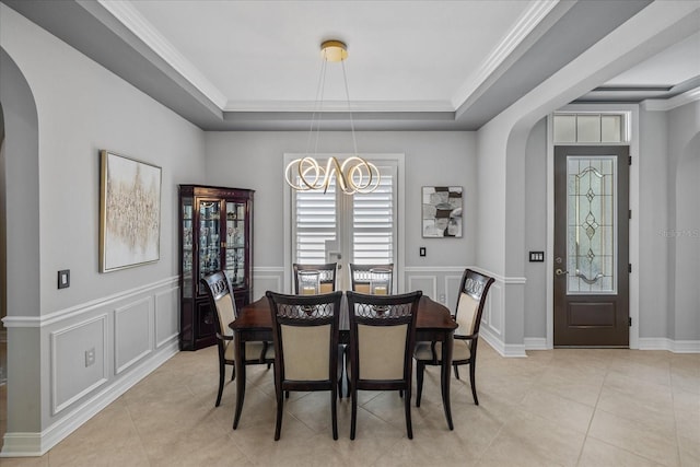 dining space with a tray ceiling, crown molding, light tile patterned flooring, and an inviting chandelier