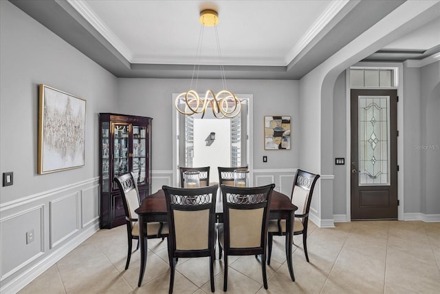 tiled dining area with a raised ceiling, crown molding, and an inviting chandelier