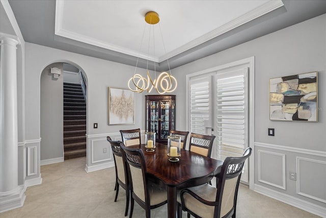 tiled dining space featuring a raised ceiling, crown molding, and an inviting chandelier