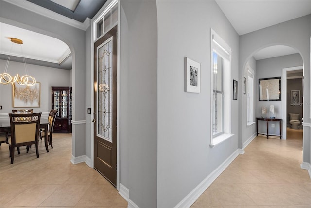 hall with a chandelier, light tile patterned floors, and ornamental molding